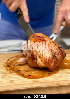 Homme coupant du poulet rôti sur une table à l'extérieur Banque D'Images