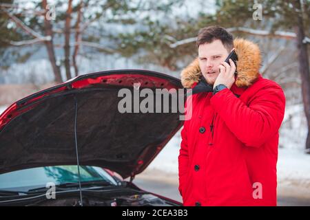 Homme debout près de Broken voiture avec le capot ouvert de l'aide d'appel Banque D'Images