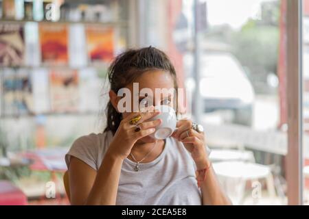 Jolie femme assise à la cafétéria et ayant une tasse de café. Banque D'Images