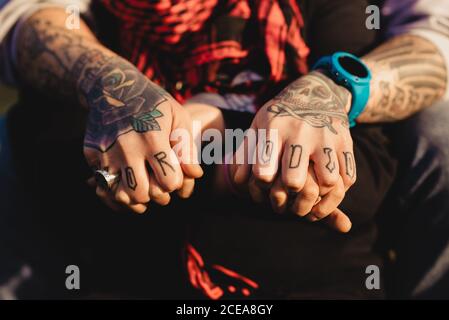 Les mains de l'homme de culture tatoueurs à anneau et regarder tenant la main de dame au foulard rouge par temps ensoleillé Banque D'Images