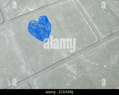 Un coeur bleu, un maladroitement dessiné en craie par un enfant main sur une surface gris-vert d'une ancienne table rayée Banque D'Images