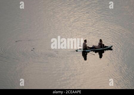 Austin, Texas, États-Unis, 18 août 2020 : un couple assis sur un paddle-board debout profite du coucher du soleil après une chaude journée d'été sur le lac Lady Bird dans le centre-ville d'Austin. ©Bob Daemmrich Banque D'Images