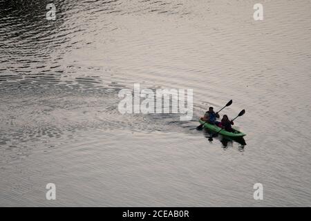 Austin, Texas, États-Unis, 18 août 2020 : les pagayeurs dans un kayak vert vif apprécient le coucher du soleil après une chaude journée d'été sur le lac Lady Bird dans le centre-ville d'Austin. ©Bob Daemmrich Banque D'Images