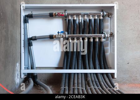 Système distributeur plomberie maison de tubes pour la distribution de l'eau, les vannes de commande accueil conduite d'eau, close-up main humaine ouvrant la vanne. Banque D'Images