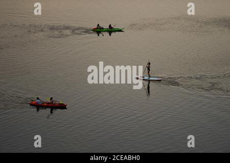 Austin, Texas, États-Unis, 18 août 2020 : un homme sur un stand-up paddle board et les pagayeurs dans des kayaks profiter du coucher du soleil après une chaude journée d'été sur le lac Lady Bird dans le centre-ville d'Austin. ©Bob Daemmrich Banque D'Images