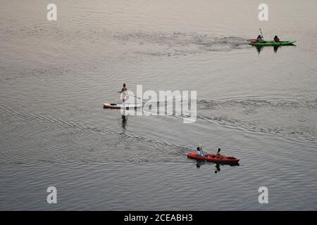 Austin, Texas, États-Unis, 18 août 2020 : un homme sur un stand-up paddle board et les pagayeurs dans des kayaks profiter du coucher du soleil après une chaude journée d'été sur le lac Lady Bird dans le centre-ville d'Austin. ©Bob Daemmrich Banque D'Images