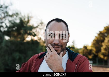 beau adulte homme dans un ensemble décontracté regardant l'appareil-photo pendant se tenant sur un fond flou de belle rue d'automne sur le soleil jour Banque D'Images