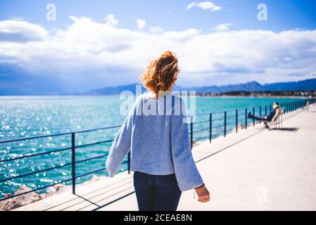 Femme debout à la main courante et regardant l'océan Banque D'Images