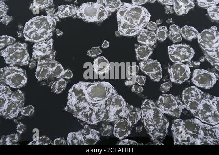 De la photo ci-dessus des plaques de glace recouvertes de neige flottant sur la surface de l'eau sombre Banque D'Images