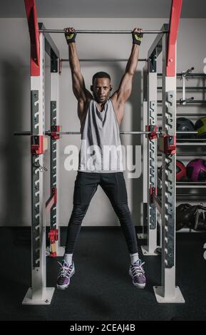 Homme afro-américain attrayant dans les vêtements de sport à l'écoute de la musique en cours le bar de la salle de sport moderne est à votre disposition Banque D'Images