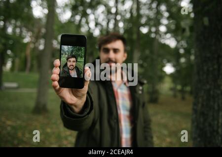 homme en forêt avec téléphone mobile pour prendre des photos Banque D'Images