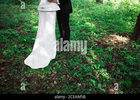 mariée et marié méconnaissables debout sur l'herbe verte de la forêt ensemble Banque D'Images