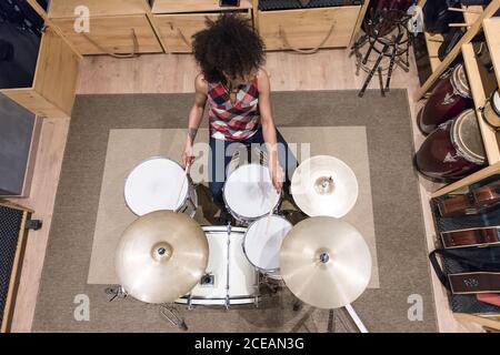 Photo ci-dessus d'une jeune femme jouant de la batterie tout en répétant dans un studio d'enregistrement. Banque D'Images