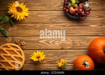 Fond de saison de Thanksgiving, bois rustique avec décoration d'automne : citrouilles, tourte, tournesols, pommes et raisin. Célébration Thanksgiving ou automne Banque D'Images