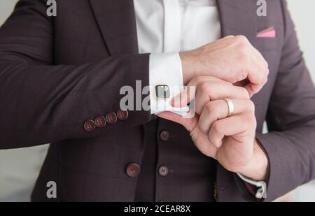 Vue d'en dessous du jeune homme souriant debout dans la chambre avec murs blancs et costume de mise Banque D'Images