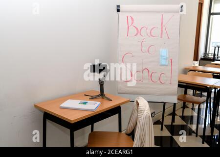 Un tableau blanc dans une salle de classe vide avec des lettres Retour à l'école et un masque médical, prêt pour l'apprentissage à distance Banque D'Images