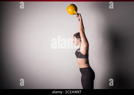 Une jeune femme sportive concentrée dans les vêtements de sport, qui augmente la kettlebell dans la salle de sport Banque D'Images