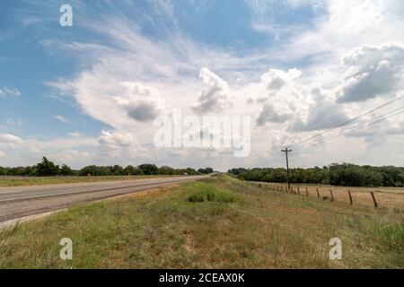 Vue sur l'autoroute du Texas avec Farm Land sur le côté De la route et des constructions cônes Banque D'Images