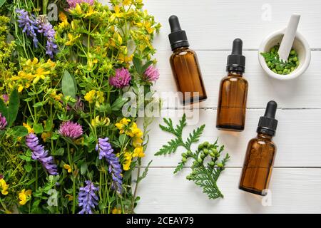 Flacons compte-gouttes d'huile essentielle, de mortier et d'herbes médicinales sur bois. Médecine alternative. Banque D'Images