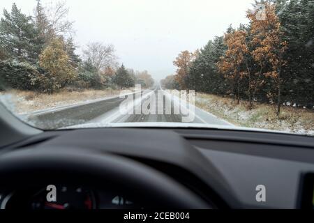 Conduite d'une voiture sur la route enneigée pendant un ciel nuageux jour d'hiver Banque D'Images