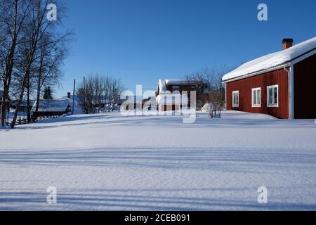Petites maisons sombres de village nordique debout près de la forêt en hiver. Banque D'Images