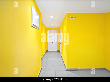 Murs jaunes avec portes blanches de couloir étroit dans moderne bâtiment Banque D'Images