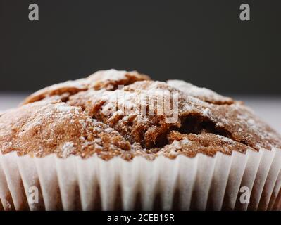 Délicieuse sauce au gâteau au chocolat avec sucre en poudre dans un emballage en papier blanc isolé sur fond gris en mise au point douce Banque D'Images