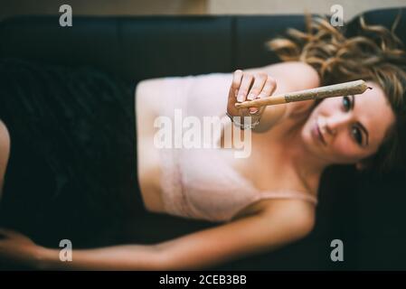 Femme allongé sur un canapé avec un joint de marijuana Banque D'Images
