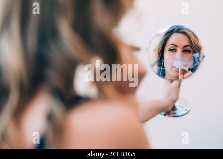 Une jeune femme fume un joint de cannabis dans le miroir Banque D'Images