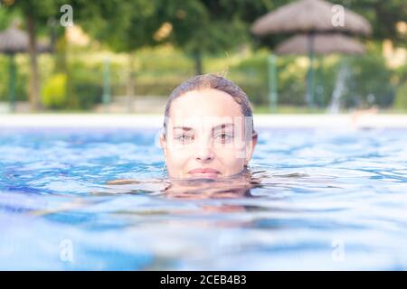 Photo d'une jeune femme attrayante qui nage dans la piscine et regarde la caméra Banque D'Images