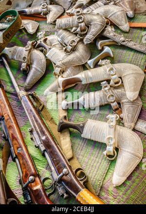 Khanjars et fusils exposés au marché du vendredi des armes à feu à Nizwa, en Oman Banque D'Images
