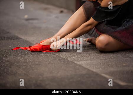 Ballerine à tête rouge avec tutu noir en train de battre des pointes de ballet rouges dans la rue Banque D'Images