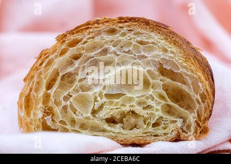 Gros plan de la texture spongieuse intérieure d'un délicieux croissant fraîchement cuit sur du textile blanc. Banque D'Images