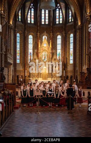 Un chœur d'enfants se produit devant le haut autel de la nef de l'église Saint-Matthias, Budapest, Hongrie. Banque D'Images