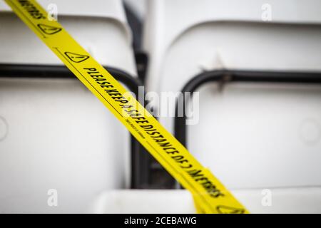 Gros plan sur des bandes de sécurité réparties sur les places assises du stade sportif, permettant aux spectateurs, aux fans et au personnel de rester à distance lors de la pandémie Covid 19. Banque D'Images