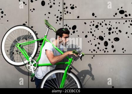 Vue latérale d'un jeune homme portant un cycle vert dans le ville Banque D'Images