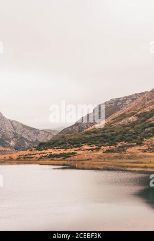 Personne en imperméable jaune allant sur la rive du lac près de wigam et colline à Isoba, Castille et Leon, Espagne Banque D'Images