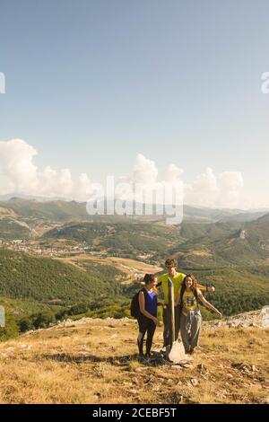 Jeune homme et deux femmes debout sur la colline sur fond de belle nature le jour nuageux Banque D'Images