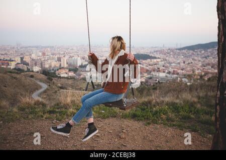 Vue latérale d'une femme méconnue dans un ensemble décontracté Faites du swing et admirez la vue magnifique de Barcelone Banque D'Images