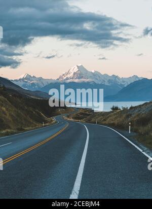 Route sinueuse d'asphalte menant à la majestueuse montagne Aoraki dans beau Soirée nuageux en Nouvelle-Zélande Banque D'Images