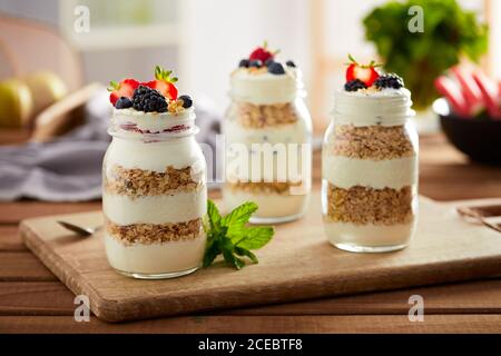 Délicieux petit déjeuner servi dans des pots en verre avec yaourt et granola sous la garniture de baies fraîches d'été Banque D'Images