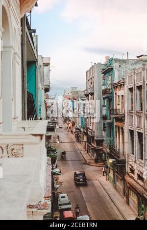 CUBA, le 14 septembre 2017 : rue étroite et pittoresque, avec des bâtiments à plusieurs étages aux intempéries des deux côtés et des voitures rétro donnant sur la route depuis le balcon Banque D'Images