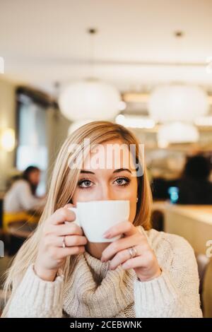 Jeune femme charmante tenant une tasse dans un café Banque D'Images