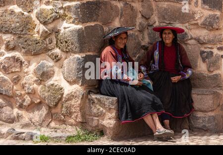 Pérou - janvier 02 2012 : deux femelles ethniques en vêtements traditionnels assis près du vieux mur de pierre le jour ensoleillé Banque D'Images