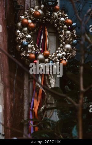 Couronne de Noël décorée de boules rouges et dorées, accrochée à l'extérieur de la maison, style ancien d'Europe centrale Banque D'Images