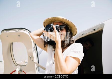 Jolie femme abaisse un avion extérieur et prend des photos. Banque D'Images