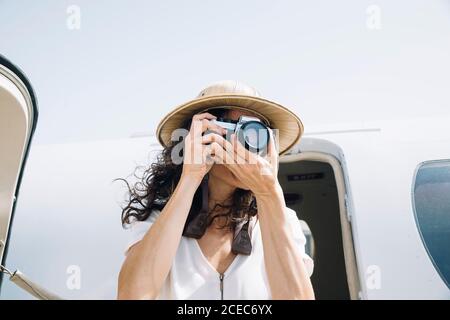 Jolie femme abaisse un avion extérieur et prend des photos. Banque D'Images