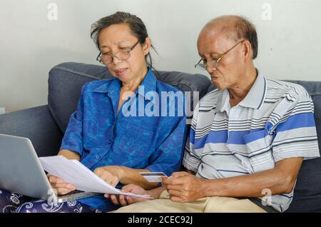 Aînés femme et homme regardant des documents d'affaires ordinateur et carte de crédit. Banque D'Images