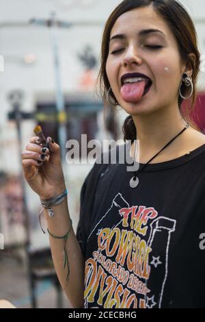 Jeune artiste avec un pinceau grimaquant à la caméra tout en créant en studio. Banque D'Images