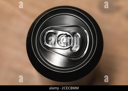 Boîte en aluminium noir brillant fermée sur une table en bois, emballage standard pour boissons non alcoolisées. Vue de dessus Banque D'Images